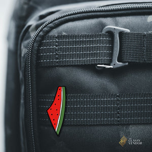Palestine Watermelon Enamel Pin pinned on a black backpack. Sold by the Classy Vendor.