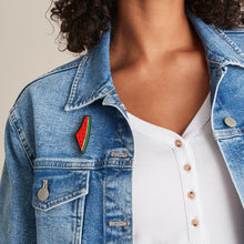 Load image into Gallery viewer, Palestine Watermelon Enamel Label Pin on a blue jean jacket worn by a female model with curly black hair. Sold by the Classy Vendor.
